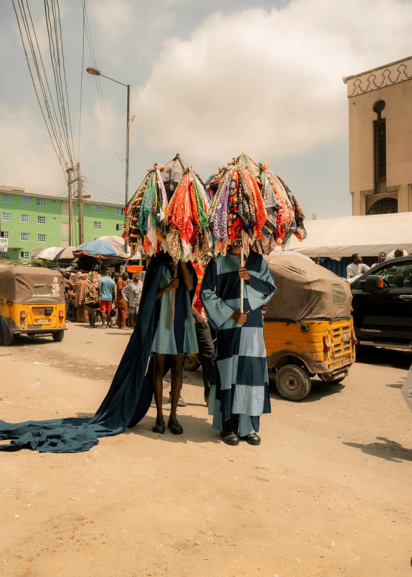 Figures under fabric umbrellas on a Lagos street